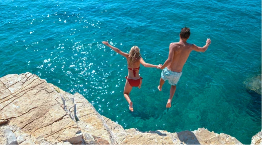 Man and woman leaping into the Pacific Ocean in Guam.